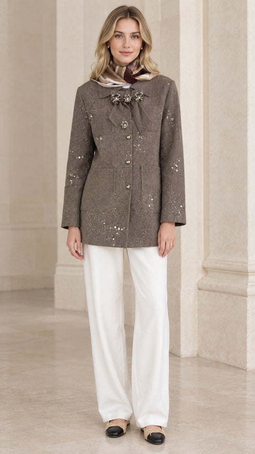Full front view of model wearing taupe sequin embellished tweed jacket with white trousers