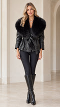 Front view of model wearing black faux leather jacket with black faux fur collar and tie belt