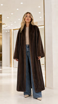 Full front view of model wearing a long dark brown plush faux fur maxi coat with wide-leg jeans