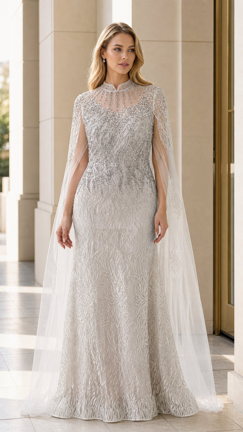 Front view of model wearing silver beaded evening gown with sheer cape overlay