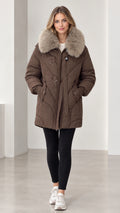 Front view of model wearing brown mid-length quilted puffer parka with plush faux fur collar