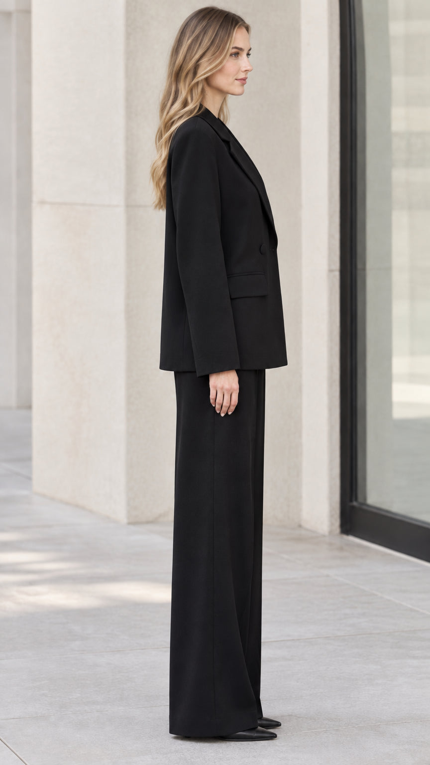 Side profile view of model wearing black two-piece wide-leg pant suit