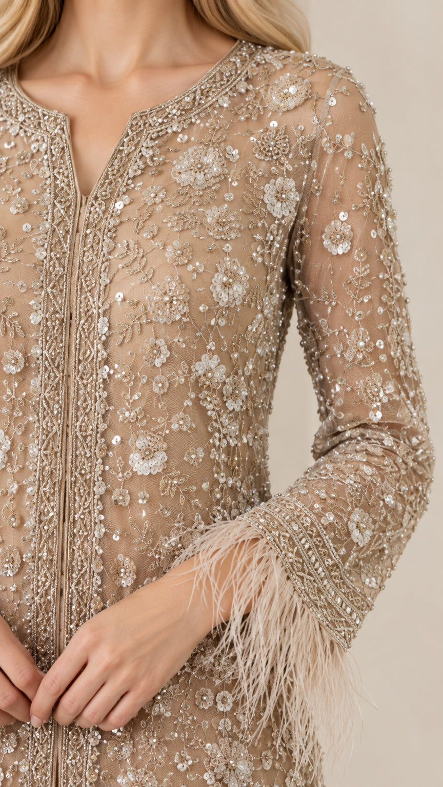 Close-up detail of intricate floral sequin embroidery and feather cuff detailing on champagne tunic